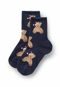 Marine sokker med et gentaget mønster af lysebrune teddy-bjørne iført røde og hvide hatte. Fremstillet af blødt stof med en glat tekstur.