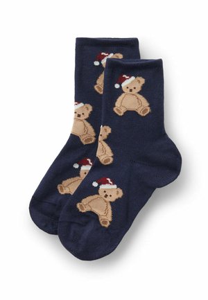 Chaussettes bleu marine présentant un motif répétitif d'ours en peluche marron clair portant des chapeaux rouges et blancs. Fabriquées en tissu doux avec une texture lisse.