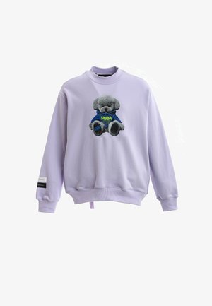 Sudadera lila claro con un oso de peluche gris con capucha azul impresa en el centro y una pequeña etiqueta en la manga izquierda.