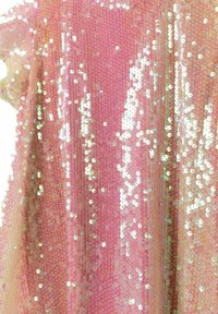 Tissu en sequins roses avec des sequins ronds irisés disposés de manière dense, créant une surface texturée qui reflète la lumière.