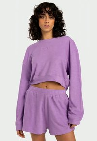 Sweatshirt court violet à manches longues et texture côtelée, associé à un short violet assorti avec une taille élastique.