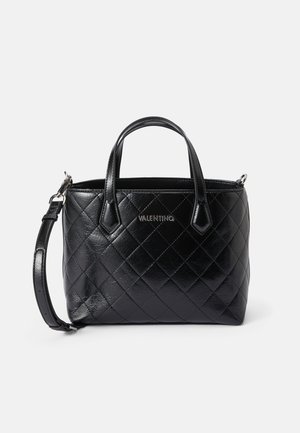 Must musta koti, millel on keedetud muster, kaks pealmist käepidet ja eemaldatav õlaline rihm. Hõbedane riistvara brändi logoga ees.