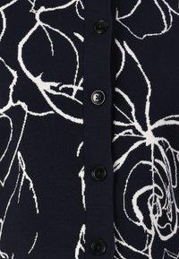 Μπλε ζακέτα με λευκό λουλούδι σχέδιο, ριμπ ύφασμα και πέντε μαύρους κουμπιά μπροστά για κλείσιμο.