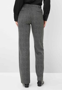 Grijze houndstooth-patroon broek met een hoge taille, rechte pijpen en twee achterzakken, gecombineerd met een zwarte lange mouwen top.