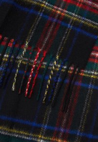 Wool scarf featuring a tartan pattern in black, green, red, and yellow with fringed edges and a soft, textured finish.