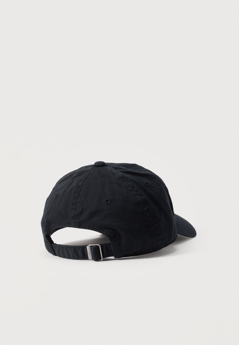 Gorra de béisbol negra ajustable mostrada desde atrás con correa de tela y hebilla metálica sobre un fondo liso y claro.