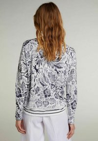 Langarm-Pullover mit floralem Muster in Marineblau auf hellgrauem Hintergrund. Gerippter Saum mit zwei Marineblauen Streifen. Weicher, strukturierter Stoff.
