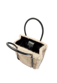 Mała torebka z miękką, beżową futrzaną zewnętrzną warstwą i czarnymi, teksturowanymi skórzanymi akcentami. Posiada dwa zakrzywione czarne uchwyty oraz zapięcie na zamek.