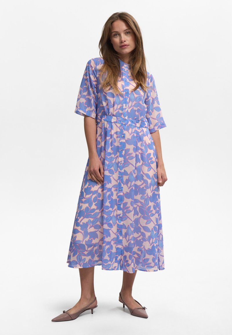 Robe longue à motifs floraux dans des teintes pastel de violet et de rose, avec un devant boutonné, des manches courtes et une taille cintrée.