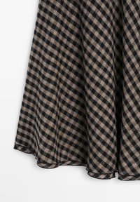Tissu à carreaux noir et beige avec une texture douce, présentant un ourlet arrondi et un motif vichy classique.