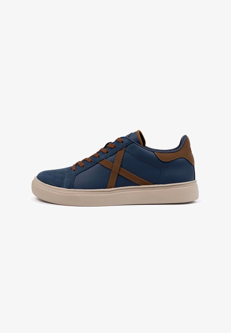 Navy blue leather sneakers with brown leather accents, lace-up design, contrasting stitching, and a beige rubber sole.