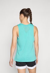 Lys turkise ermeløse tanktop med et mesh trekantdetalj på baksiden, sammen med svarte shorts med hvit kant.