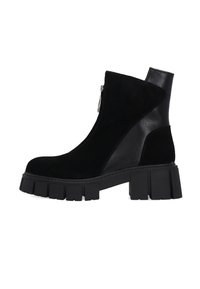 Zwarte enkelboot van een combinatie van suede en leer. Beschikt over een zijrits en een chunky, gestructureerde platformzool.