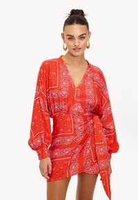 Vestido rojo de wrap con estampado de paisley, mangas largas y escote en V. Hecho de tela ligera, cuenta con un lazo en el lado y cintura elástica.