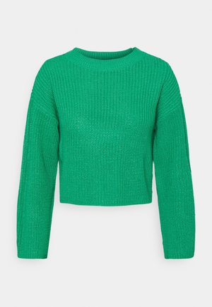 Pull en maille vert à manches longues, col rond et coupe légèrement raccourcie et carrée sur un fond clair uni.