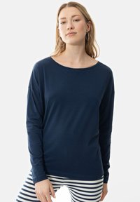 Marineblauwe longsleeve shirt met een wijde halslijn en een relaxte fit. Zacht, lichtgewicht materiaal. Gecombineerd met gestreepte leggings voor contrast.