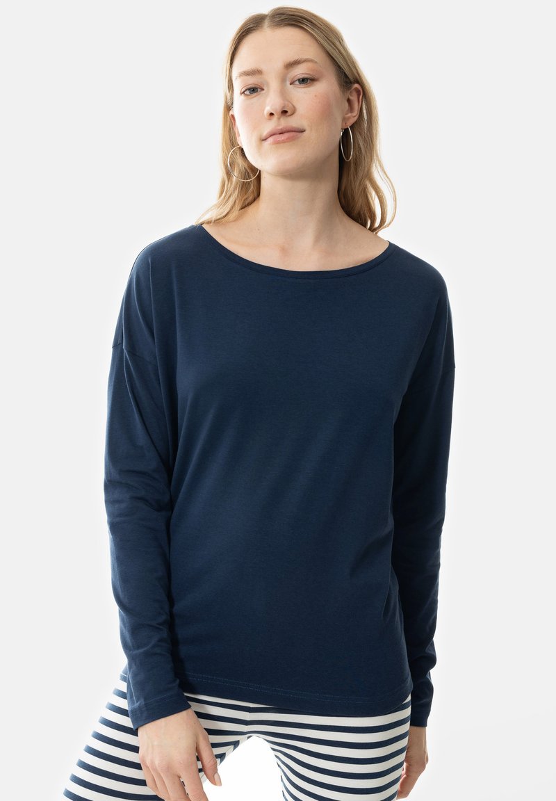 Marinblå långärmad tröja med vid halsringning och avslappnad passform. Mjuk, lättviktsmaterial. Kombinerad med randiga leggings för kontrast.