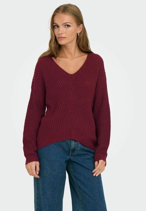 Bordeaux gebreide trui met een V-hals, lange mouwen en een textuurdesign. Gepaard met blauwe jeans, met een losse pasvorm en casual stijl.