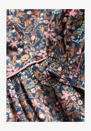 Chemise à fleurs avec un fond bleu marine foncé, ornée de motifs multicolores de fleurs et de feuilles, fermeture à boutons, et bordure rose autour de l'encolure.