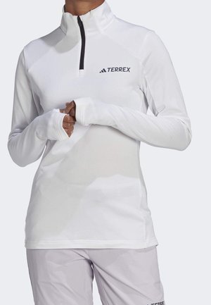 Sudadera deportiva blanca de manga larga con agujeros para el pulgar y cremallera negra, con el logo negro "TERREX" en el pecho.