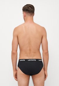 Bóxer negro para hombres con una cinturilla que presenta la marca "Levi's" en blanco. Tejido suave, diseño minimalista y ajuste ceñido.