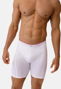 Caleçons blancs en tissu extensible, présentant un design ajusté, une taille avec un accent rouge, et une texture lisse.