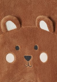 Weiches braunes Stofftier in Form eines Bärenkopfes mit runden Ohren, schwarzen Augen, einer schwarzen Nase und weißen Wangen.