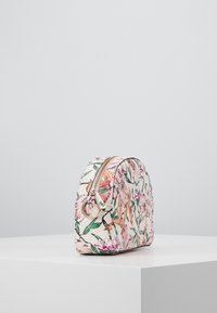 Cosmetisk taske med blomstermønster i pink og grøn, rund form, lavet af tekstureret materiale, med en guldfarvet lynlås og hardware detaljer.