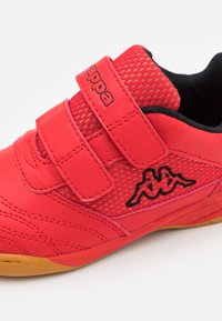 Rød atletiksko med overdel i mesh og syntetisk læder, med velcro-lukninger, tekstureret design og en sort logo på siden.