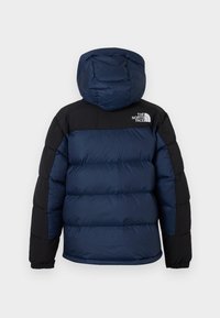 Jakna s punjenjem u mornarskoplavoj boji s crnim ramenima. Uključuje kapu i elastične manžete za udoban fit. Prikazan je logo The North Face.