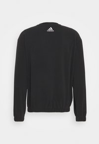 Schwarzes Sweatshirt mit langen Ärmeln, elastischen Bündchen und Saum. Mit einem weißen Adidas-Logo auf dem oberen Rücken. Glatte Textur.
