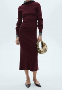 Ensemble pull en tricot côtelé bordeaux et jupe avec un col gris, assorti à un sac texturé marron à motif serpent et des escarpins noirs à bout pointu.