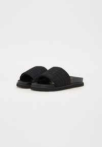 Sandale negre din material textil împletit, cu un capac moale, design cu vârf deschis și talpă plată din cauciuc cu textură subtilă.