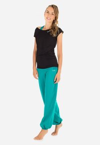 Black short-sleeve shirt paired with teal jogger pants. The pants are loose-fitting with elastic cuffs at the ankles.