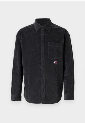 Camisa de corduroy negra para hombre con mangas largas, cierre de botones al frente, bolsillo en el pecho y detalle de logo en rojo, blanco y azul en el lado izquierdo.