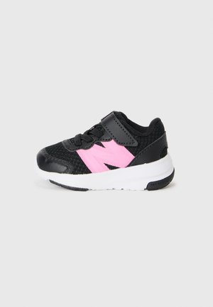 Schwarze Kleinkind-Sneaker mit pinkem "N"-Logo, schwarzen Schnürsenkeln, Klettverschluss und weißer Sohle vor einem schlichten Hintergrund.