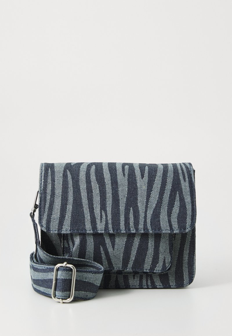 Bolso bandolera de tela con estampado de cebra en azul oscuro y azul claro, que cuenta con un cierre de solapa y una correa ajustable. Material de denim texturizado.