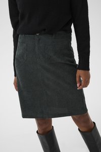 Dark green corduroy skirt featuring front pockets, a straight cut, and a button closure. Styled with a black sweater and knee-high boots.