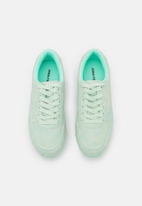Sapatilhas atléticas em verde menta com um upper em malha texturizada, design com atacadores, colarinho acolchoado e sola de borracha lisa. Nome da marca por dentro.