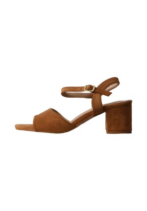 Brown suede open-toe sandal with low block heel and adjustable ankle strap with gold buckle on a white background.