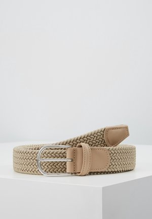Beżowy tkany pasek z jasnobrązowymi skórzanymi akcentami i srebrną metalową klamrą, zwinięty na białej powierzchni na jednolitym tle.