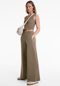 Khaki ribbed crop top with round neck and sleeveless design, paired with wide-leg khaki trousers featuring side pockets and elastic waistband.