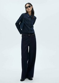 Dark denim shirt with a pointed collar, paired with wide-leg dark denim pants. Accented with a black belt and sunglasses, featuring a smooth texture.