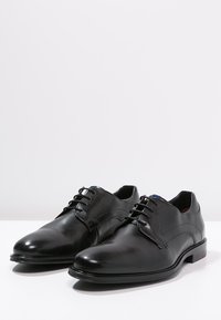 Scarpe eleganti in pelle nera con una finitura liscia, punta arrotondata e design con lacci. Presentano cuciture sottili e un tacco a profilo basso.