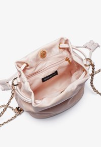 Sac seau en satin rose avec quincaillerie dorée, fermeture à cordon de serrage et doublure intérieure douce. Comprend une poche intérieure avec fermeture éclair.