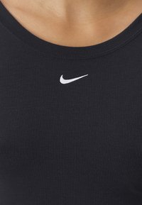 Czarny prążkowany top na ramiączkach z okrągłym dekoltem i małym białym logo Nike na piersi. Miękka tekstura oraz dopasowany krój.