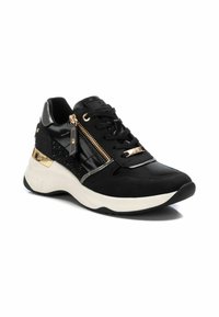 Deportiva negra con una suela blanca contrastante. Presenta acentos texturizados en negro, detalle de cremallera dorada y un material brillante y suave.