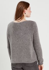 Suéter gris de punto con escote redondo, puños y dobladillo acanalados. Textura suave con un corte holgado, con detalles mínimos en la parte posterior.