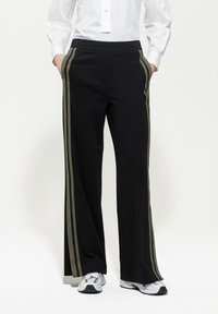 Schwarze weite Hosen mit olivgrünen Streifen an den Seiten, aus weichem Material, mit einem bequemen elastischen Bund.