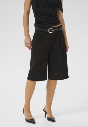 Zwarte cropped broeken met een riem, met een slanke textuur en stijlvol ontwerp. Gecombineerd met zwarte puntige hakken.